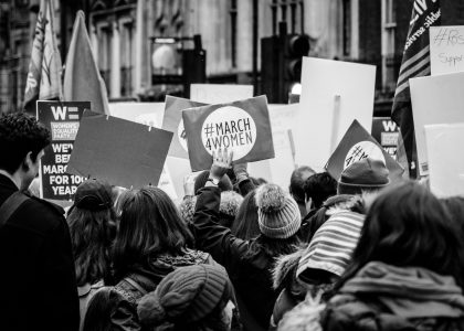 grayscale photo of group of people performing rally on street